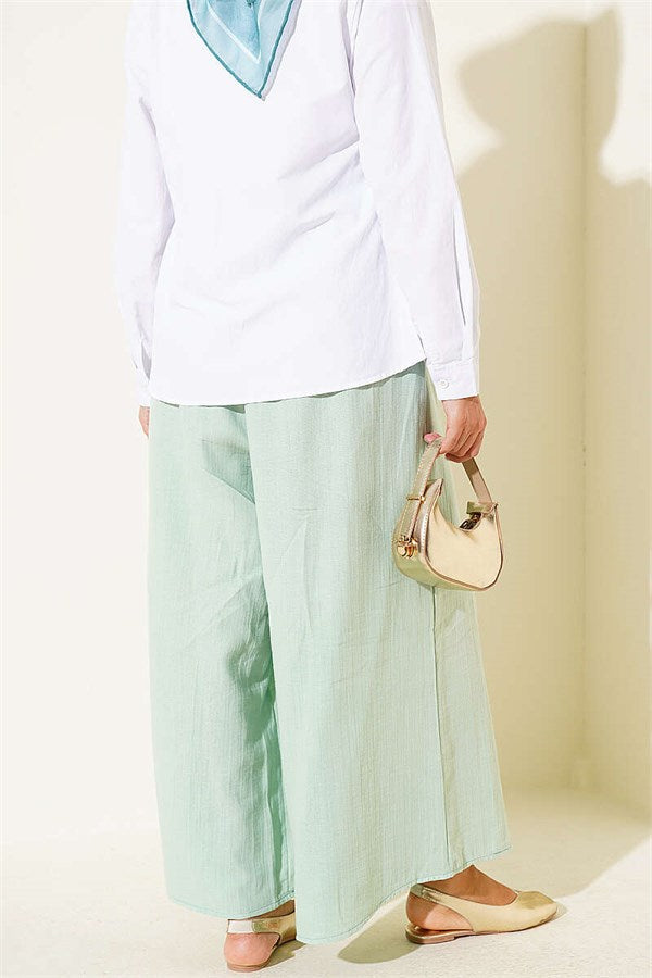 Loose-fitting muslin trousers with elastic waistband, light green.