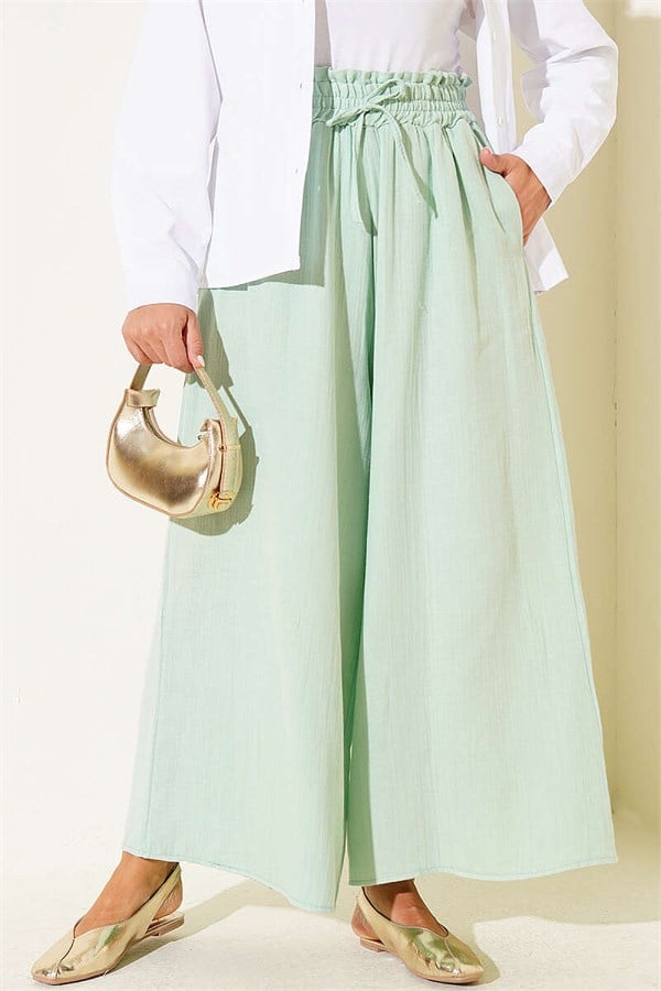 Loose-fitting muslin trousers with elastic waistband, light green.