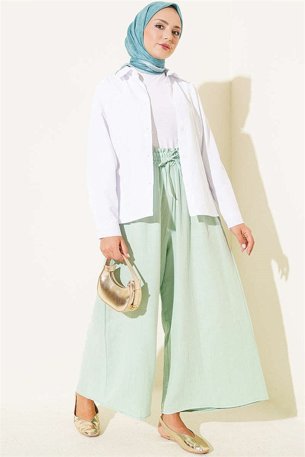 Loose-fitting muslin trousers with elastic waistband, light green.