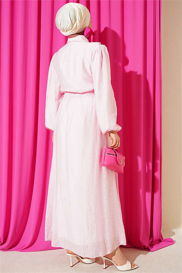 Two-piece set in pink with gold button detail and ruffled skirt.
