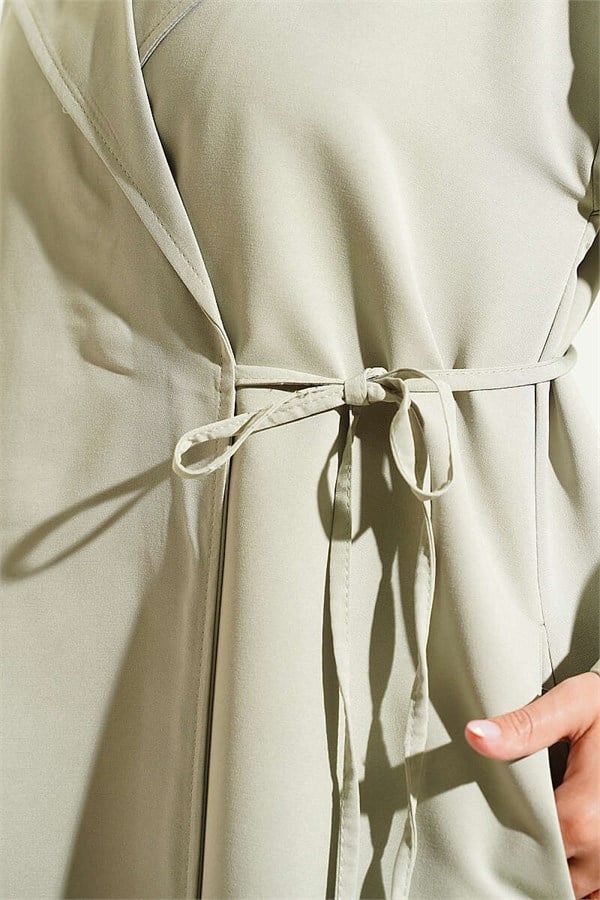 Double-breasted trench coat with drawstring closure, light green.