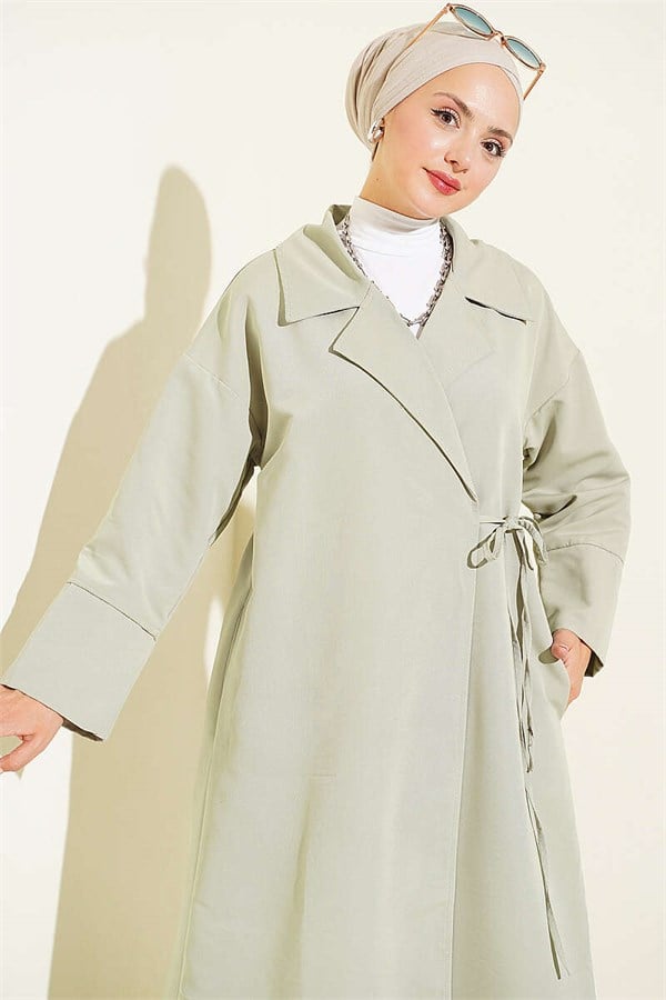Double-breasted trench coat with drawstring closure, light green.